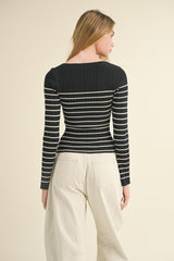 woman wearing a black and white striped ribbed long sleeve top and beige wide-leg pants, showing the back view