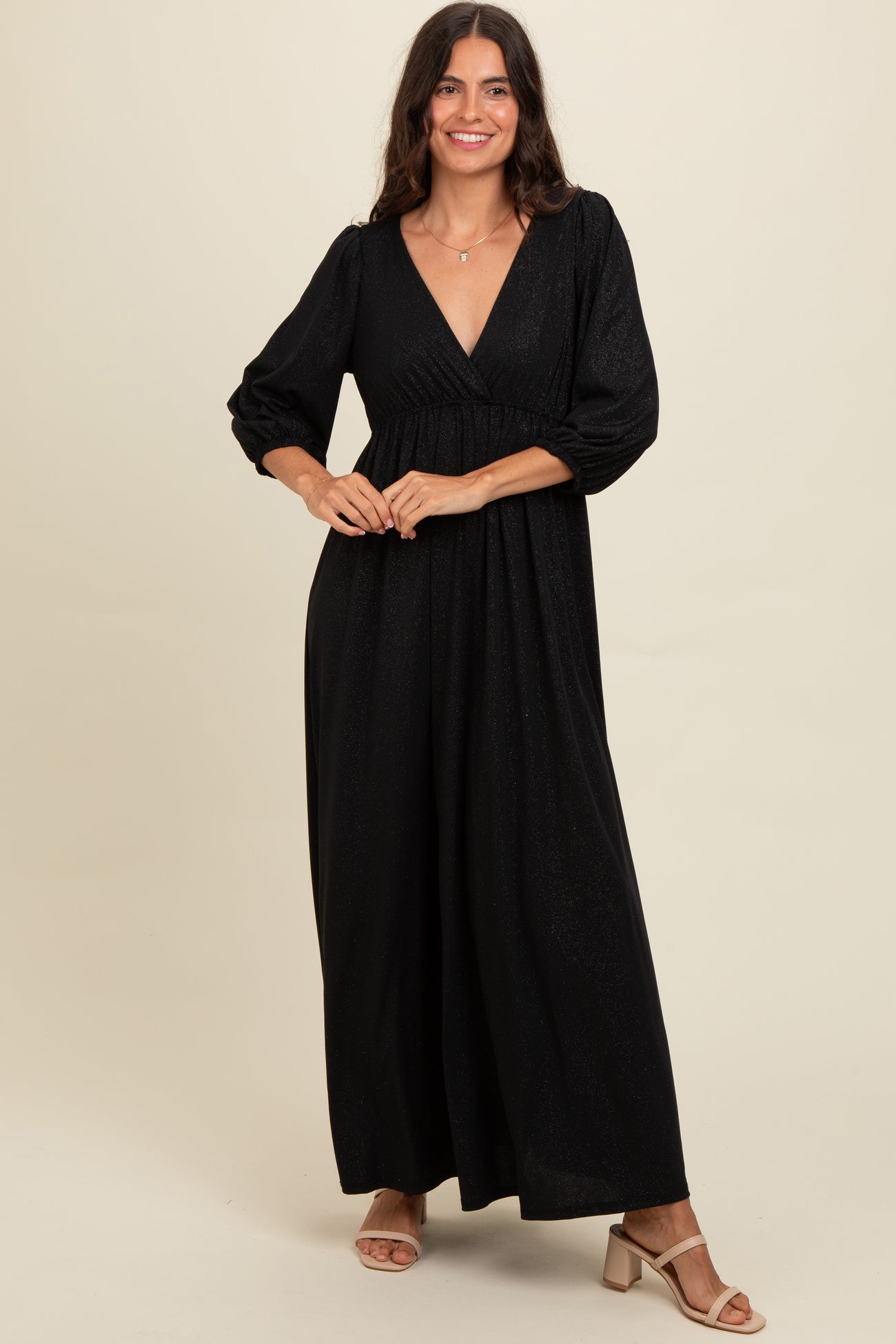 woman wearing a black sparkling maxi dress with a plunging neckline and puff sleeves
