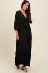 woman wearing a black sparkly maxi dress with a v-neck and puff sleeves, standing in a relaxed pose