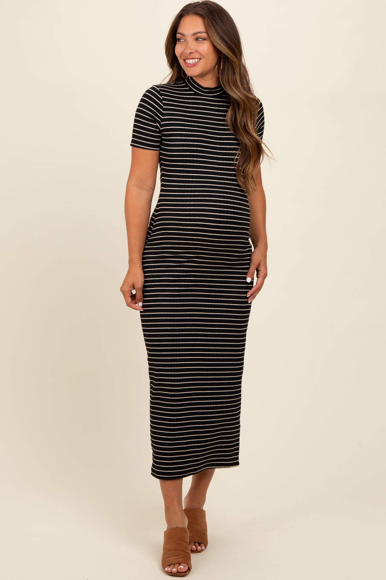 woman wearing a black and white striped maternity dress with a fitted silhouette and short sleeves