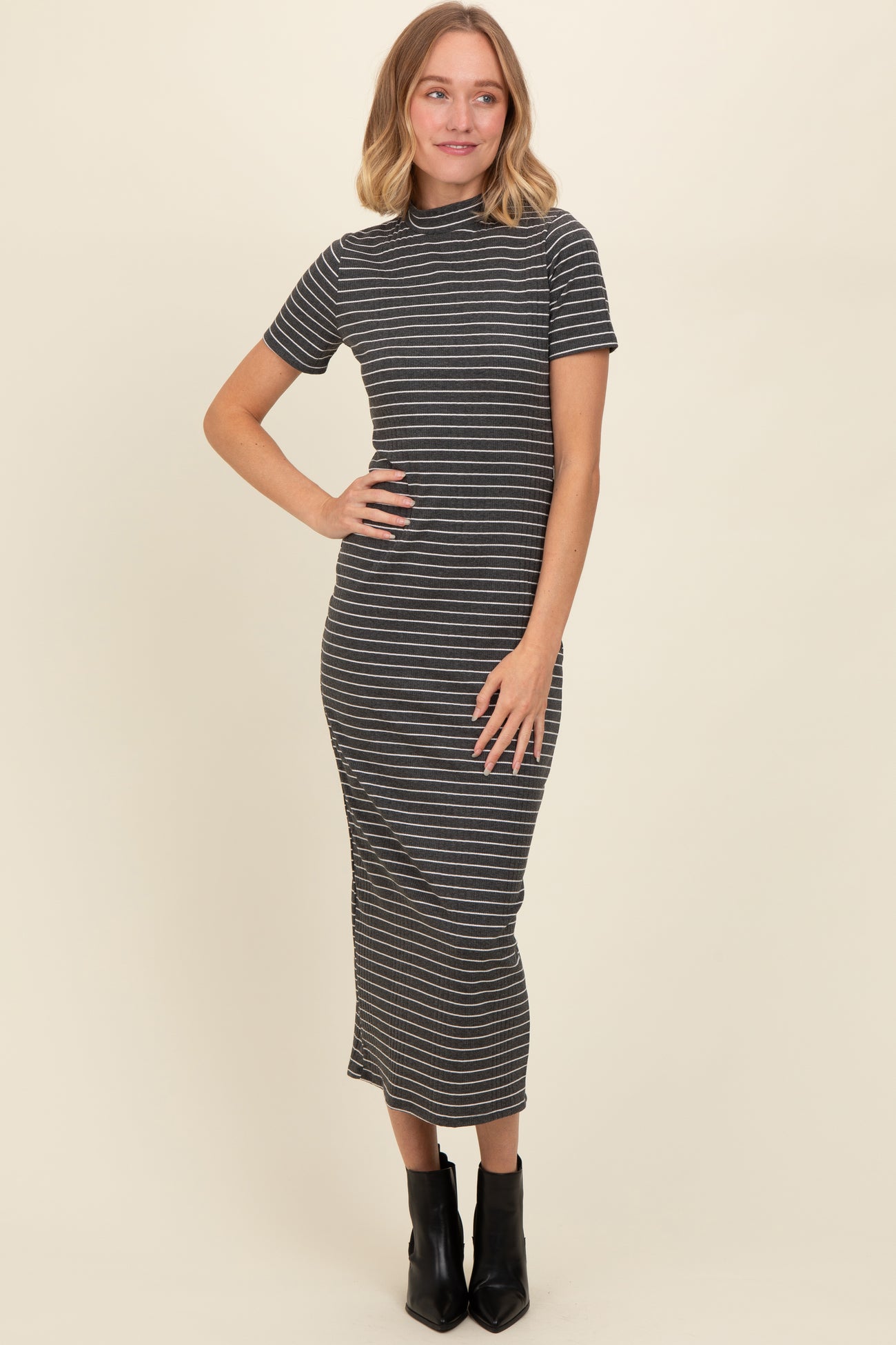 woman wearing a black and white striped fitted midi dress with short sleeves and a high neckline