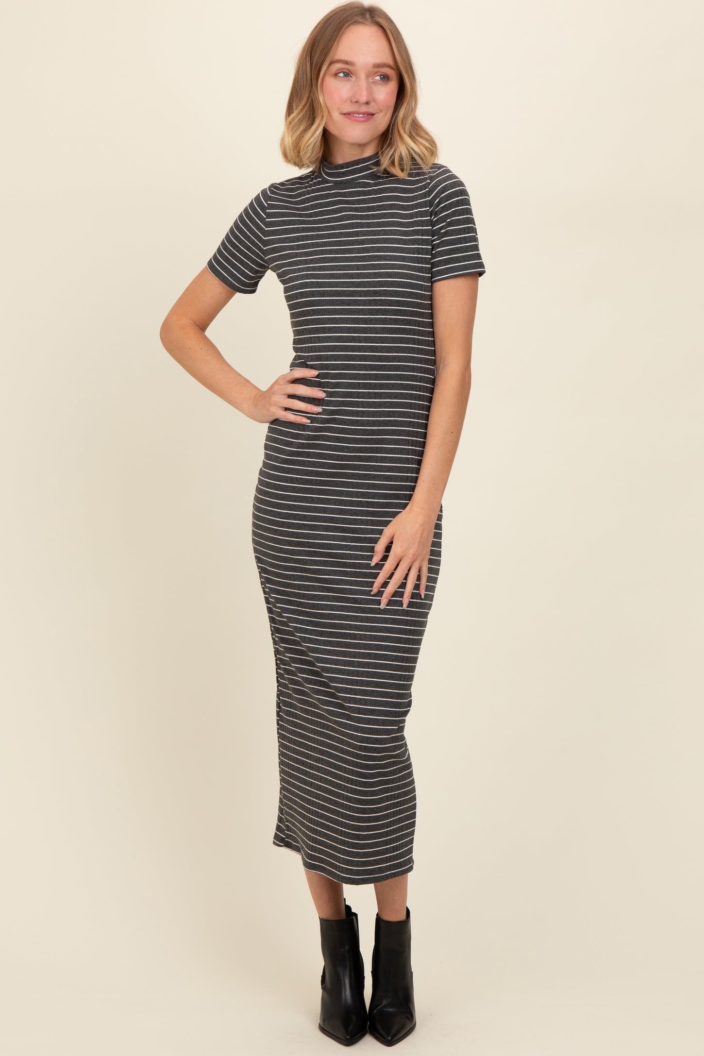 woman wearing a black and white striped fitted midi dress with short sleeves and a high neckline
