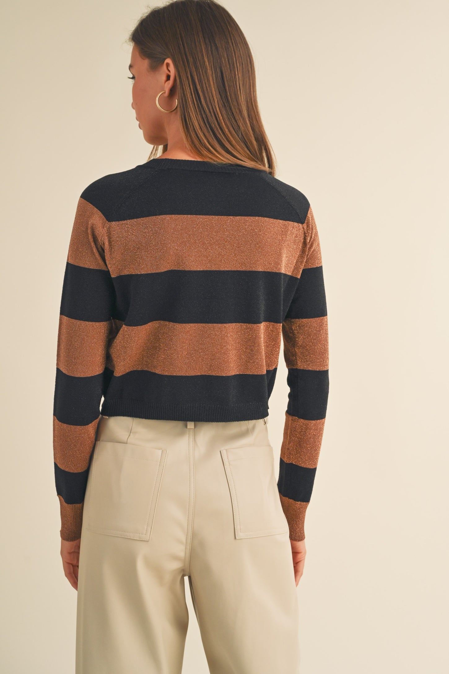 woman wearing a brown and navy striped long sleeve sweater, shown from the back with a relaxed fit