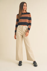 woman wearing a brown and black striped sweater with beige wide-leg pants and black shoes