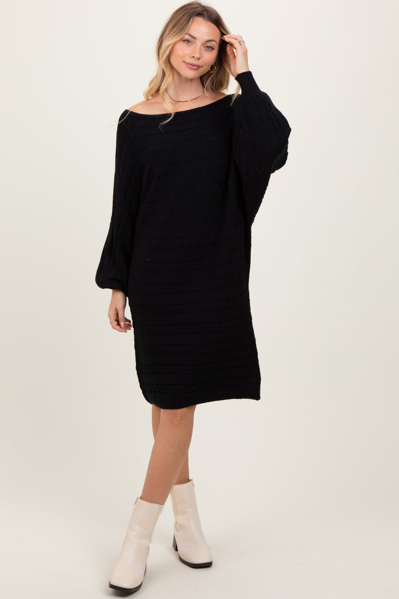 woman wearing a black oversized knitted sweater dress with puffed sleeves and a relaxed fit