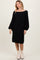 woman wearing a black cable knit sweater dress with balloon sleeves and creamy ankle boots