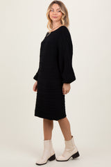 woman wearing a black cable knit long sleeve dress and beige ankle boots