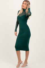 woman wearing a fitted dark green midi dress with sheer long sleeves and a high neck
