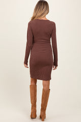 woman wearing a brown ribbed long sleeve maternity dress, seen from the back, with knee-high tan boots
