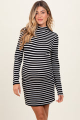 woman wearing a black and white striped maternity dress with a high neck and long sleeves, showing her baby bump