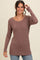 woman wearing a mauve long sleeve ribbed top with a rounded neckline and curved hemline