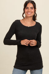 woman wearing a black long sleeve ribbed top with a scoop neckline and relaxed fit