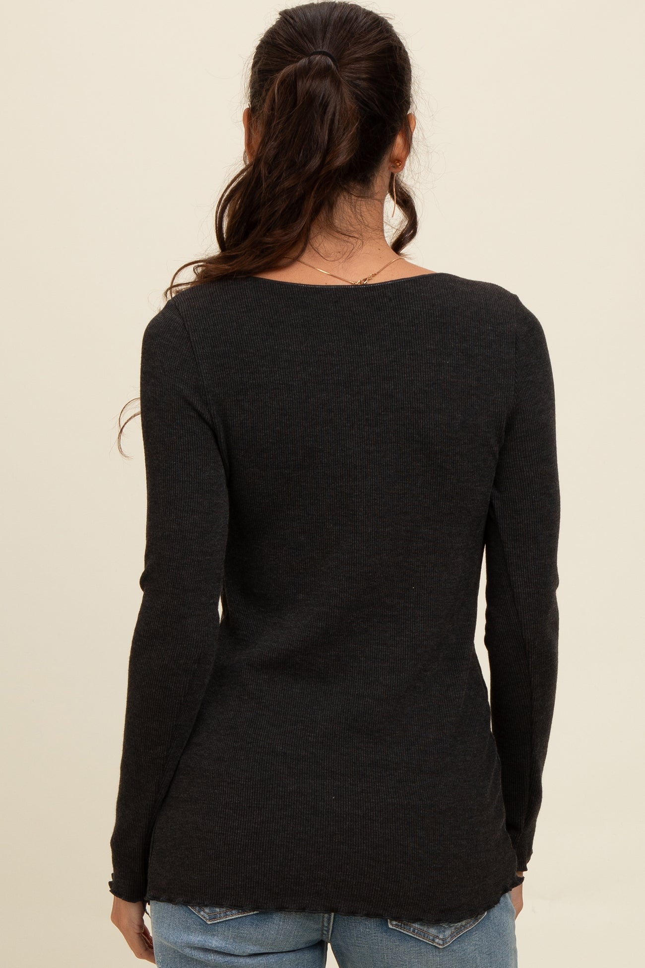woman wearing a black long sleeve ribbed sweater, viewed from the back, paired with blue jeans