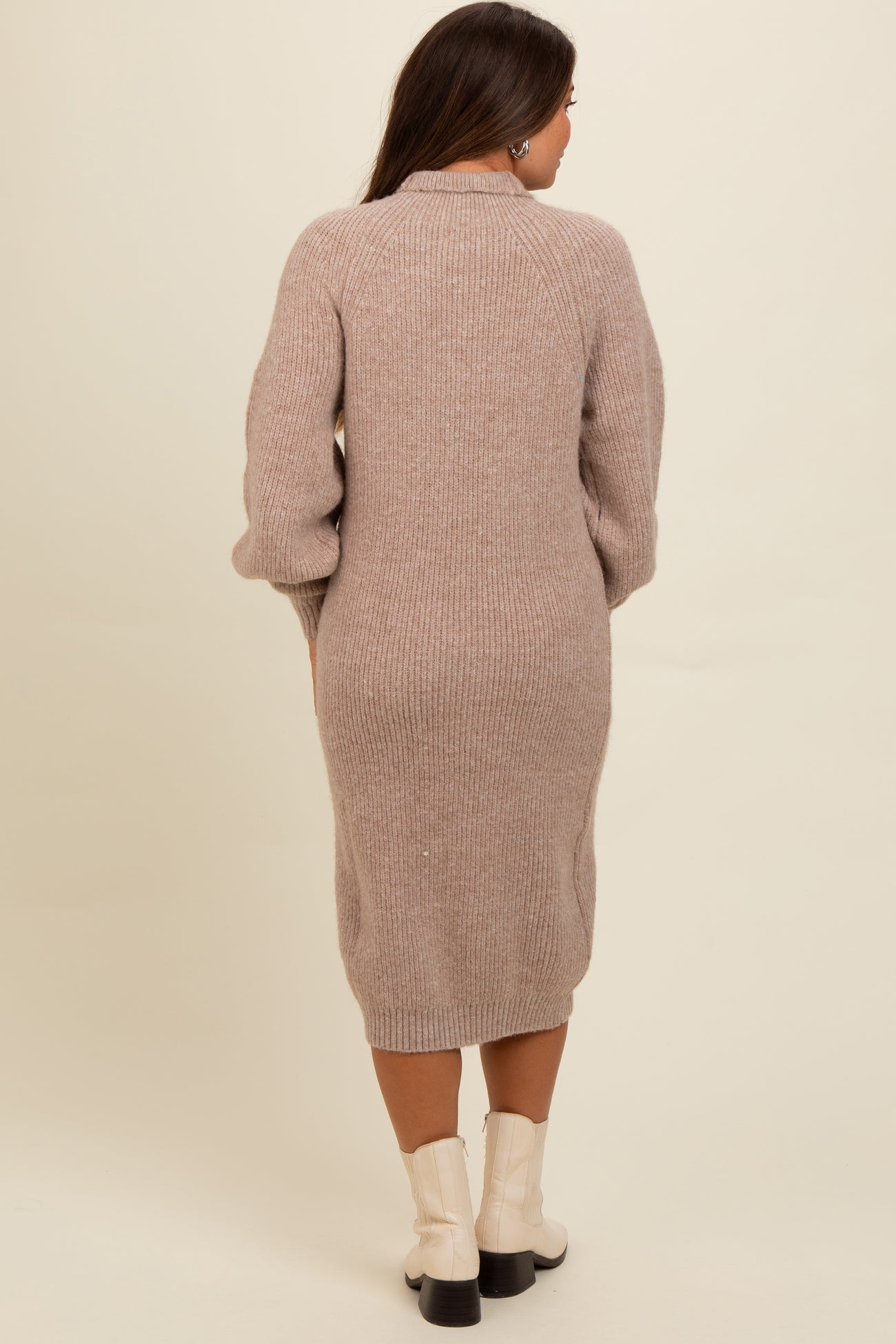 woman wearing a light beige long sleeve maternity sweater dress with a fitted silhouette and ribbed texture