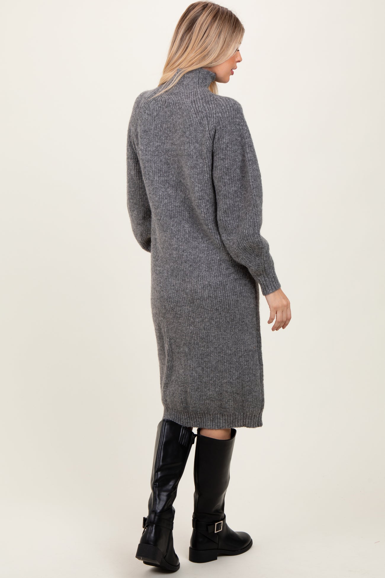 woman wearing a gray knitted sweater dress with a high collar and long sleeves, viewed from the back