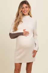woman wearing a cream and brown color block maternity sweater dress, showing her baby bump