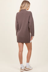 woman wearing a taupe oversized knit sweater dress with long sleeves and a high neckline, seen from the back