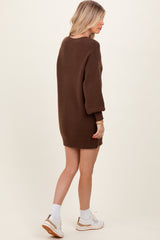 woman wearing a brown oversized sweater dress with balloon sleeves and white sneakers, shown from the back