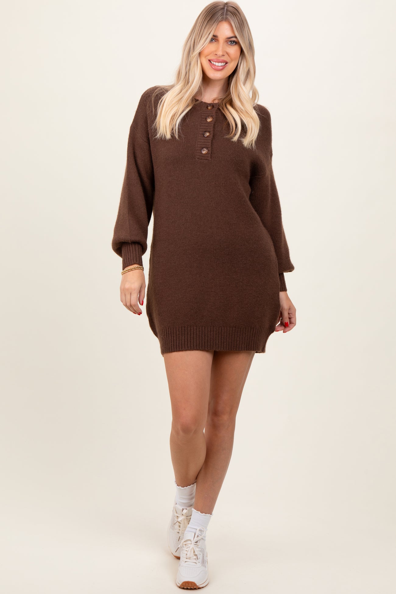 woman wearing a chocolate brown oversized sweater dress with button details and balloon sleeves