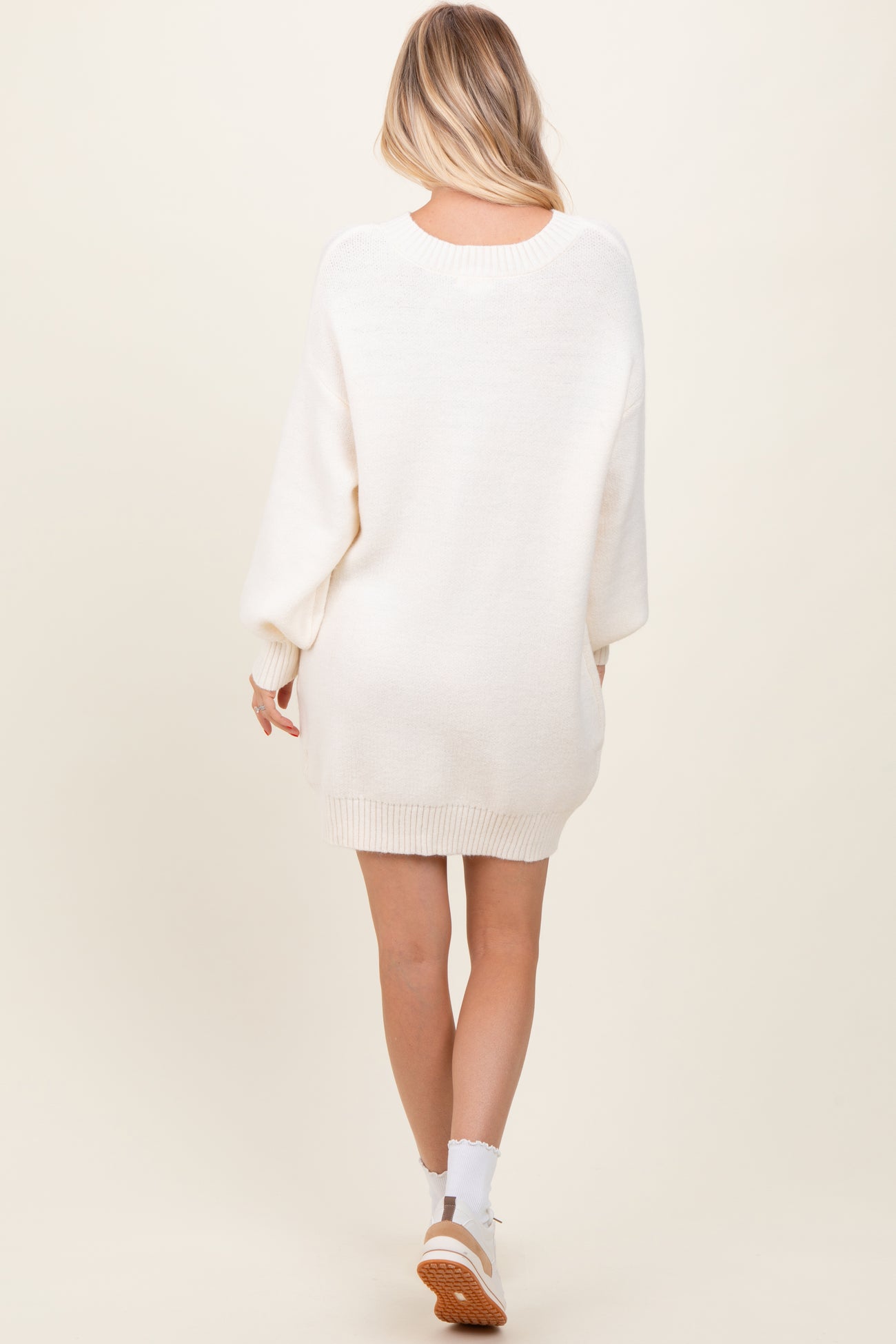 woman wearing a beige oversized sweater dress with long sleeves and a relaxed fit, shown from the back