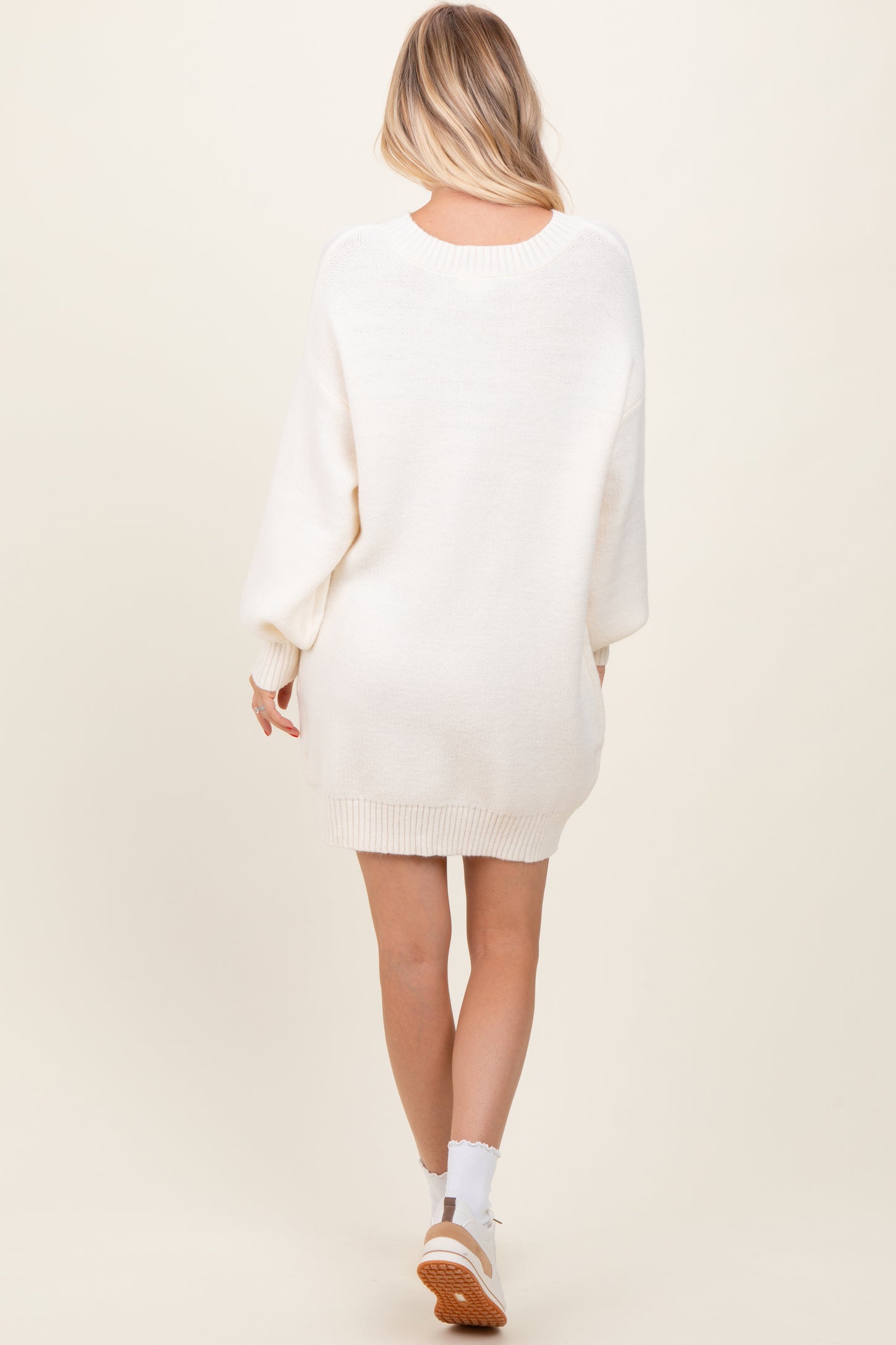 woman wearing a beige oversized sweater dress with long sleeves and a relaxed fit, shown from the back