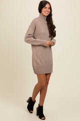 woman wearing a taupe oversized turtleneck sweater dress and black ankle booties