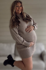 woman wearing a beige long sleeve maternity sweater dress and holding her baby bump