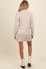 woman wearing a light beige maternity sweater dress with a turtleneck and ribbed hem, styled for comfort
