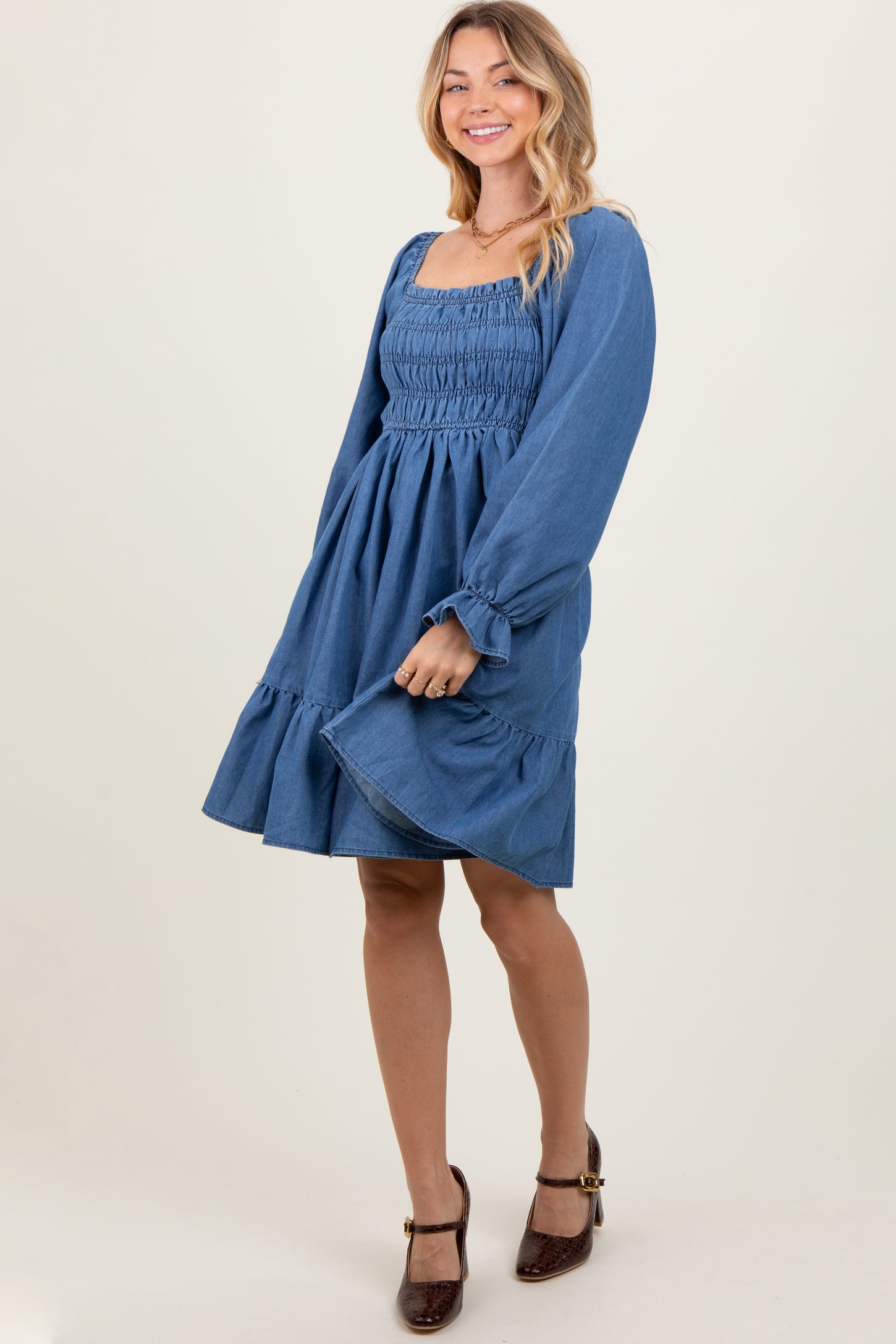 woman wearing a denim blue smocked dress with balloon sleeves and a ruffled hem
