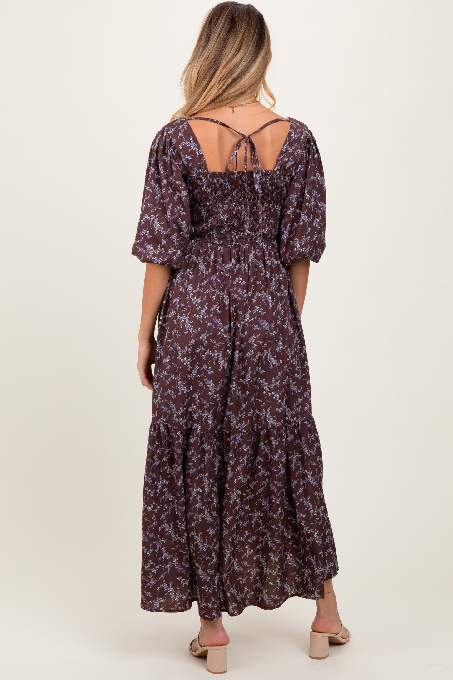 woman wearing a brown floral maternity maxi dress with puff sleeves and a smocked back, showing part of her baby bump