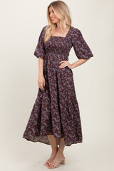woman wearing a brown floral maxi dress with puff sleeves and a smocked bodice, standing and smiling