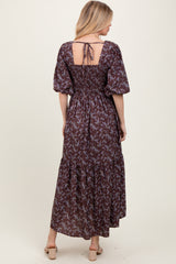 woman wearing a brown floral maxi dress with puff sleeves and a tie-back detail