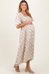 woman wearing a floral print maternity dress with puff sleeves and a tiered hem, holding her baby bump