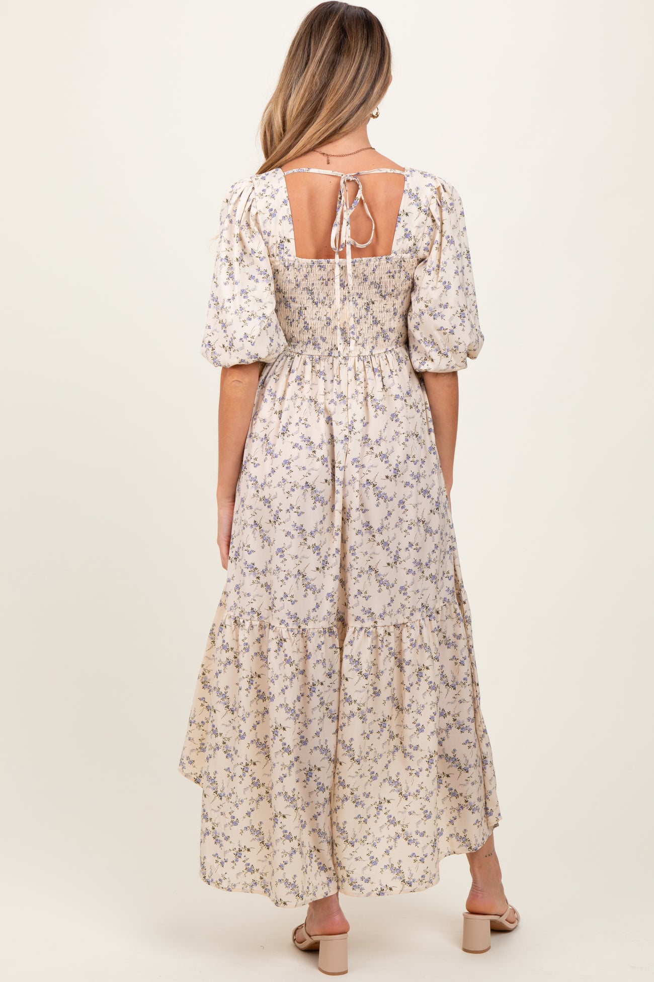 woman wearing a floral maxi maternity dress with puff sleeves and a tie back detail