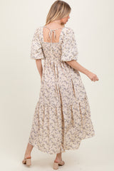 woman wearing a floral maxi dress with puff sleeves and back tie detail, styled in a light beige color