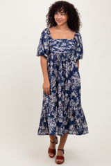 woman wearing a navy blue floral midi dress with puff sleeves and a tiered skirt