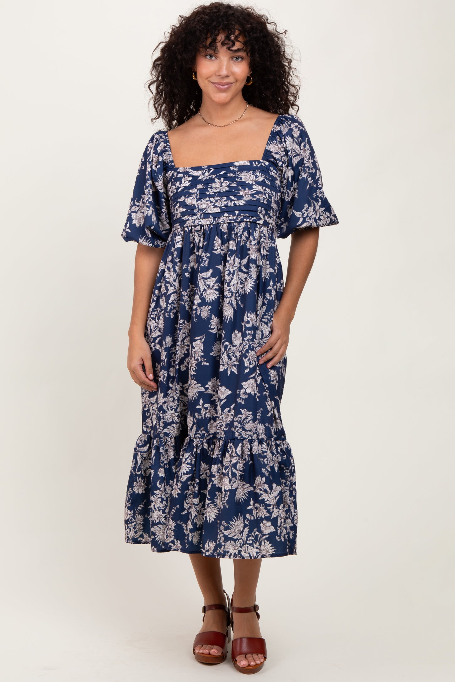 woman wearing a navy blue floral midi dress with puff sleeves and a square neckline