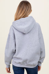 woman wearing a gray oversized hoodie, showing the back view, part of maternity wear