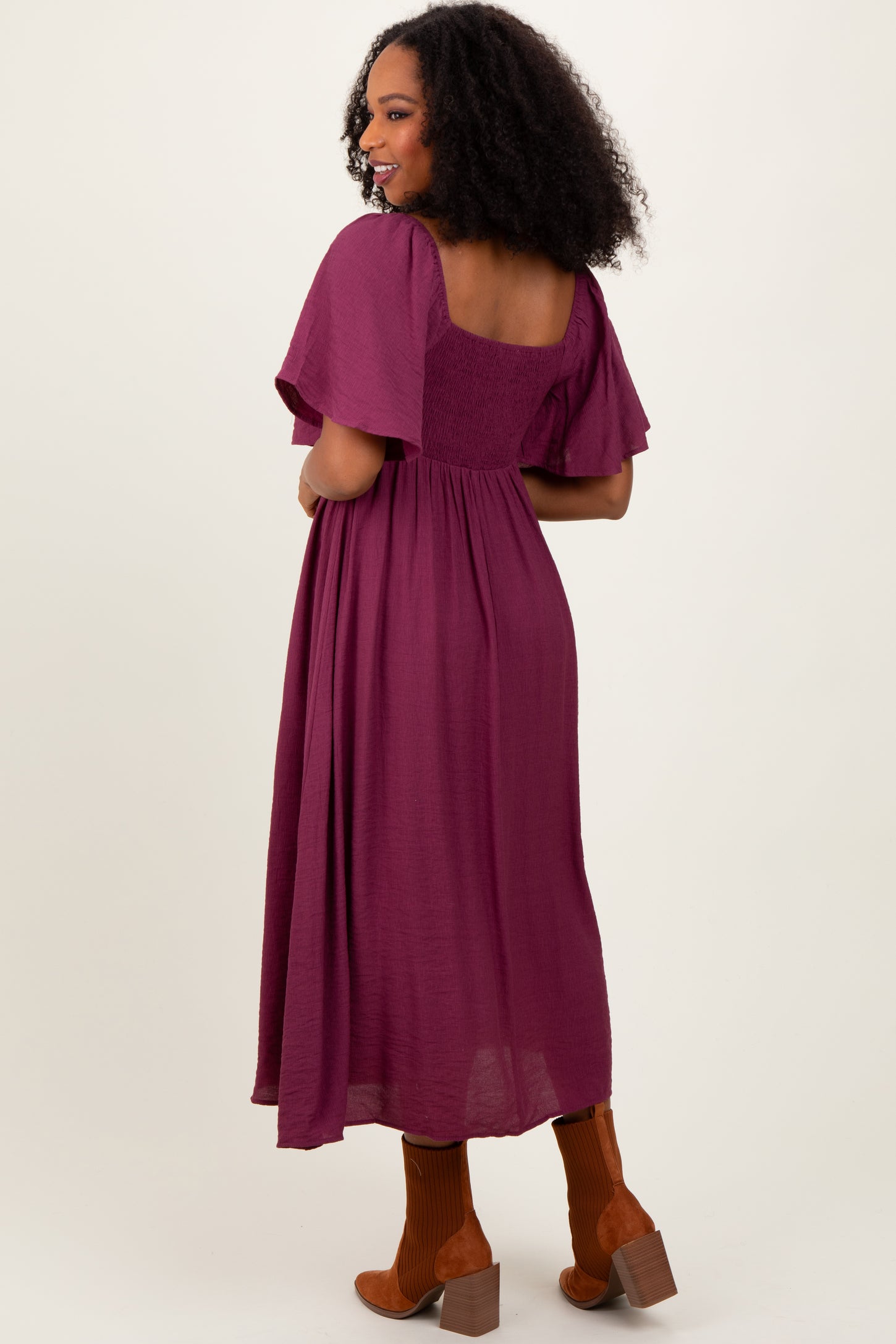 woman wearing a burgundy flutter sleeve midi dress with a square back and a flowy hem