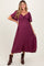 woman wearing a burgundy maternity midi dress with a tie front and short sleeves, showcasing her baby bump