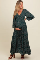 woman wearing a dark green floral maternity maxi dress and holding her baby bump