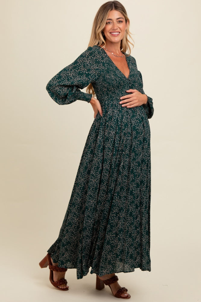 woman wearing a dark green floral maternity maxi dress and holding her baby bump