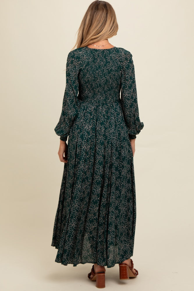 woman wearing a dark green floral maternity maxi dress with long sleeves, showing a flowy silhouette from the back