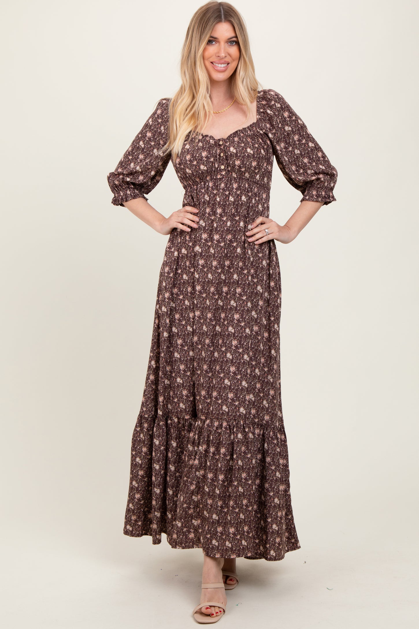 woman wearing a brown floral maxi dress with puff sleeves and a tiered skirt