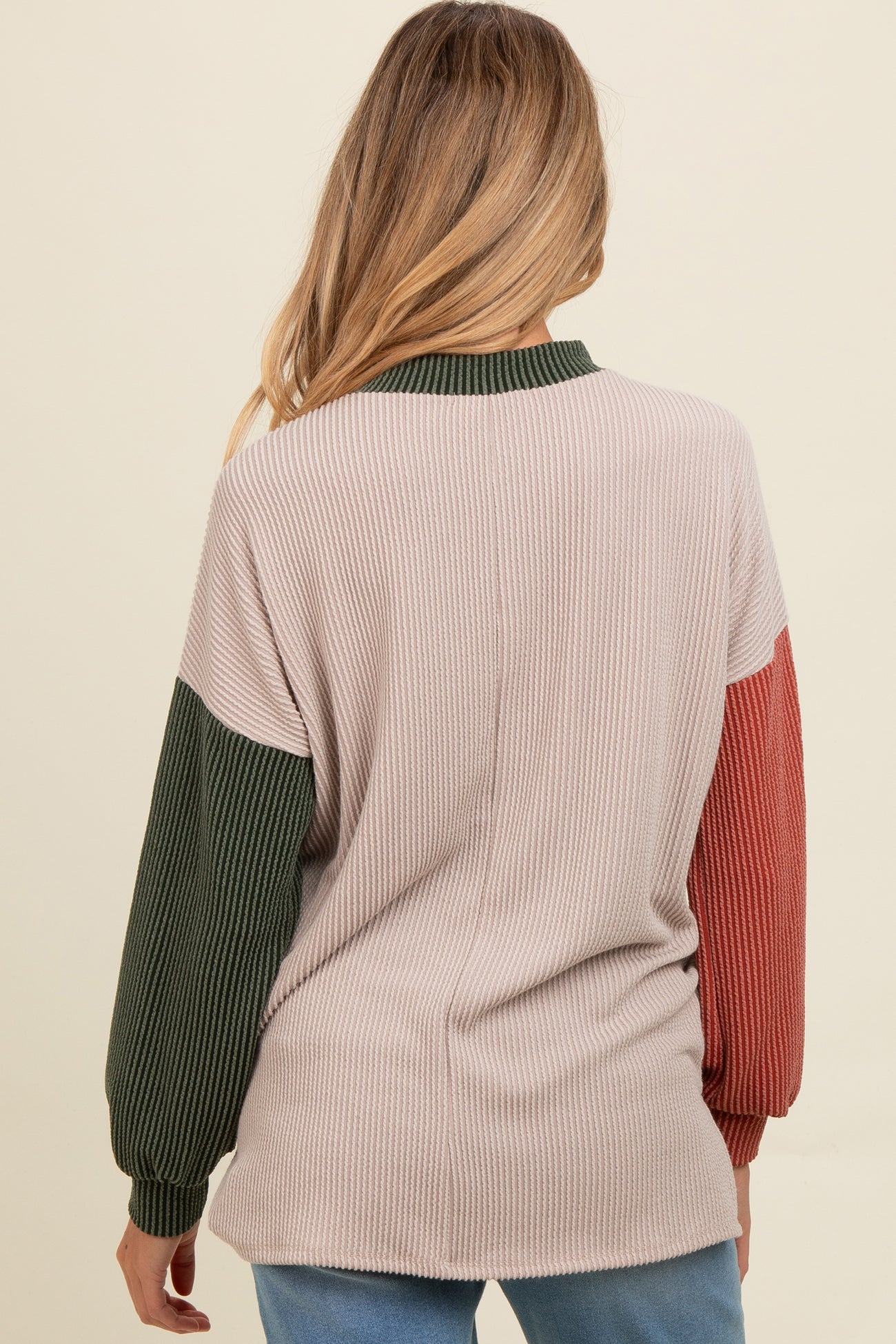 woman wearing a colorblock ribbed maternity sweater in beige, green, and rust from the back