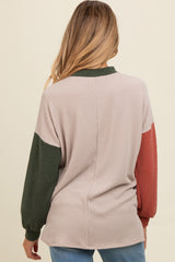 woman wearing a colorblock ribbed maternity sweater in beige, green, and rust from the back
