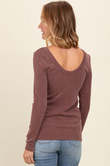woman wearing a maroon ribbed long sleeve top with a scoop back and paired with light blue jeans