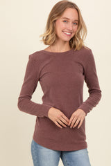 woman wearing a mauve ribbed long sleeve top with a round neckline and fitted sleeves