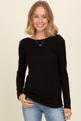 woman wearing a black ribbed long sleeve top and blue jeans, smiling at the camera