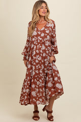 woman wearing a rust floral maternity maxi dress with long sleeves and a gathered empire waist, holding her baby bump
